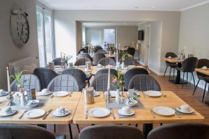 comedor con mesas y sillas y reloj en Hotel Landhaus Knappmann, en Essen