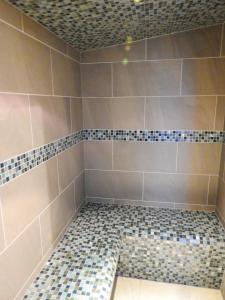 a bathroom with a shower with a tiled floor at House of Juniper in Broadford