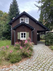 德勒斯登的住宿－Cottage am Heiderand，棕色的房子,有白色的窗户和一些鲜花