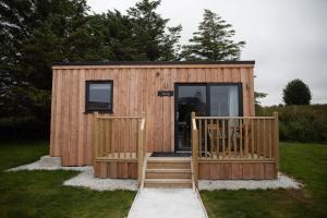 a small wooden cabin with a porch and stairs at The Cabins - House of Juniper in Broadford