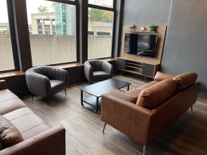 a living room with couches and a tv and windows at DerbyCity Plush Loft Gather in Style by Hollyhock in Louisville