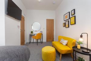 a bedroom with a bed and a yellow couch and a chair at Charles Alexander Short Stay - Charnley House Apartments in Blackpool