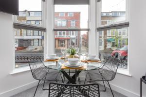 une salle à manger avec une table, des chaises et des fenêtres dans l'établissement Charles Alexander Short Stay - Charnley House Apartments, à Blackpool