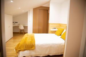 a bedroom with a white bed with yellow pillows at RAJABAi in Almansa