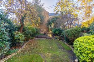 a garden with benches and trees and a building at 5 MIN TO CASTLE & SHOPS - CHARMING CHARACTER HOME in Windsor