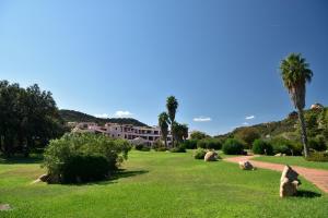 um parque com palmeiras e um edifício ao fundo em Bagaglino I Giardini Di Porto Cervo em Porto Cervo