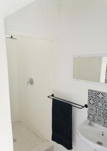 La salle de bains blanche est pourvue d'un lavabo et d'un miroir. dans l'établissement Bokkomblommetjie, à Lambertʼs Bay