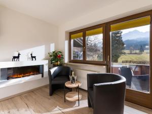a living room with a fireplace and two chairs at Appartementhaus FICHTERN in Sankt Johann in Tirol