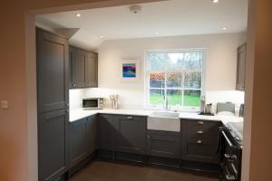 a kitchen with gray cabinets and a sink and a window at Parkside, The Loch Ness Cottage Collection in Inverness