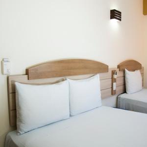 um quarto com 2 camas e almofadas brancas em Larison Hotéis - Porto Velho em Porto Velho