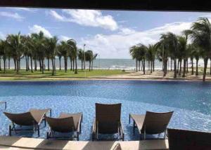 a swimming pool with chairs and a view of the ocean at Aquiraz Riviera in Aquiraz +18 photos