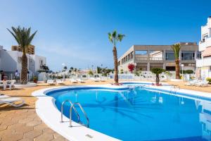 a large swimming pool with palm trees and buildings at Las Vistas Cristianos by Welcome Tenerife in Los Cristianos