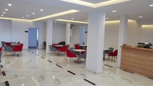 restauracja z czerwonymi krzesłami i stołami w budynku w obiekcie Relax Mea Hotel w Sarandzie