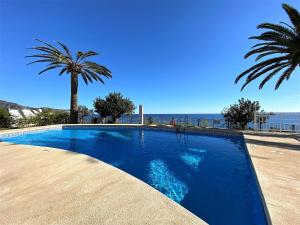 a blue swimming pool with a palm tree and the ocean at Tuhillo 2D Seaview Apartments Casasol in Nerja