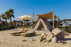 a tent and two chairs on a sandy beach at Bab Al Nojoum Hudayriyat Camp in Abu Dhabi