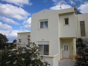 a white house with a blue sky in the background at Sunshine Villa in Gennadi