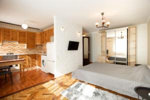 a bedroom with a white bed and a kitchen at Уютная квартира в центре in Mykolaiv