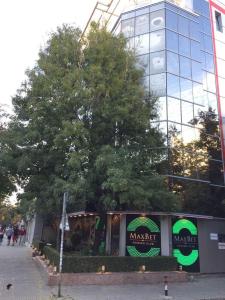 um grande edifício de vidro com uma árvore em frente em Self-Check Apartment Lilia 5 next to 24 hours food and drink shop and free parking area em Sófia
