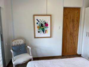 1 dormitorio con 1 cama, puerta de madera y silla en Hacienda WF - Casa 1, en José Ignacio