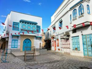 a street with white buildings and blue doors at Maison d'hôte Chama in Kairouan