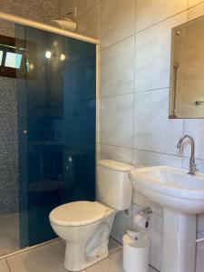a bathroom with a toilet and a sink and a shower at Casa Solana - confortável, em rua calma, no centro do Rosa in Imbituba