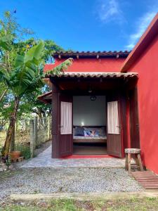 a red building with a bed in it at Casa Solana - confortável, em rua calma, no centro do Rosa in Imbituba