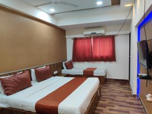 a hotel room with two beds and a television at Hotel Nova Prime in Ahmedabad