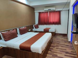 a hotel room with two beds and a television at Hotel Nova Prime in Ahmedabad