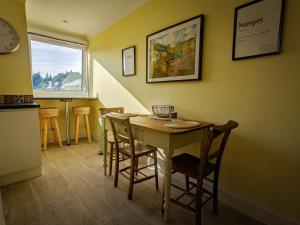comedor con mesa, sillas y ventana en Beautiful Spacious Central Flat, Pitlochry, en Pitlochry