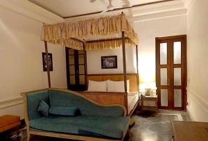 a bedroom with a canopy bed with a couch at The Rajbari Bawali in Kolkata