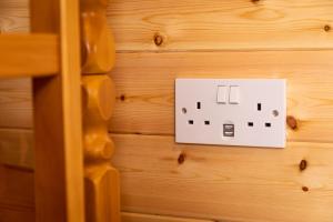 un interrupteur lumineux sur un mur en bois dans l'établissement Camping Pods Wood Farm Holiday Park, à Charmouth