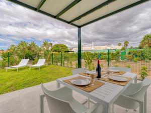 a white table with white chairs and a bottle of wine at Bungalow nuevo con jardín y piscina/ Newly renovated Bungalow with private garden and swimming pool in Maspalomas