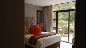 een slaapkamer met een bed met oranje kussens en een raam bij Zimbali Suites 223 in Ballito +24 foto's