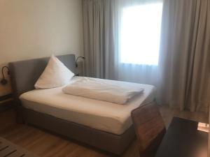 Cette chambre comprend un lit avec des oreillers blancs et une fenêtre. dans l'établissement Altstadthotel Millipp, à Beilngries