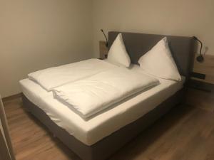 Una cama con sábanas blancas y almohadas. en Altstadthotel Millipp en Beilngries