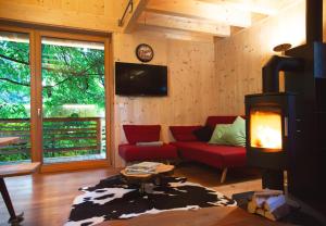 a living room with a red couch and a fireplace at Laugen Lodge in San Pancrazio dʼUltimo