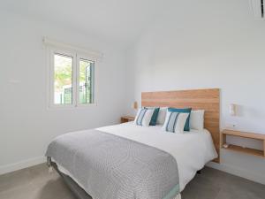 a white bedroom with a large bed with blue pillows at Bungalow nuevo con jardín y piscina/ Newly renovated Bungalow with private garden and swimming pool in Maspalomas