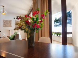 un jarrón con flores rojas sentado en una mesa en Residenze Holiday Park, en Ponte di Legno