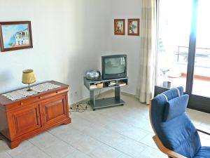 un salon avec une chaise bleue et une télévision dans l'établissement Apartment Residence Miralago - Utoring Apt- A6 by Interhome, à Piazzogna