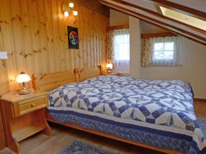 Schlafzimmer mit einem Bett mit einer blauen und weißen Bettdecke in der Unterkunft Apartment Museum by Interhome in Grächen