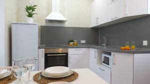 a kitchen with white cabinets and a table with chairs at Nikhouse apartment Krasniy put' in Omsk