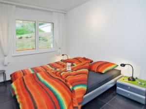 a bedroom with a bed with a colorful blanket and a window at Apartment Edelweiss D by Interhome in Leukerbad +11 photos