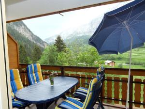 una mesa azul con sillas y una sombrilla en el balcón en Apartment Edelweiss D by Interhome en Leukerbad