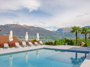 a swimming pool with chairs and a view of the mountains at Apartment Residence Miralago - Utoring Apt- B15 by Interhome in Piazzogna