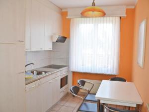 eine Küche mit orangefarbenen Wänden sowie einem Tisch und Stühlen in der Unterkunft Apartment Corallo - Utoring-23 by Interhome in Ascona