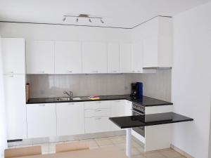 eine weiße Küche mit einem Waschbecken und weißen Schränken in der Unterkunft Apartment Corallo - Utoring-22 by Interhome in Ascona
