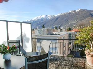einen Balkon mit einem Tisch, Stühlen und Bergen in der Unterkunft Apartment Corallo - Utoring-25 by Interhome in Ascona
