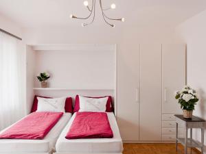 2 Betten in einem weißen Zimmer mit roter Bettwäsche in der Unterkunft Apartment Double Room-2 by Interhome in Ascona