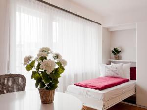 a white room with a table with a vase of flowers at Apartment Double Room-2 by Interhome in Ascona