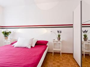 1 Schlafzimmer mit einem Bett mit rosa Bettwäsche und 2 Tischen in der Unterkunft Apartment Junior Suite-8 by Interhome in Ascona